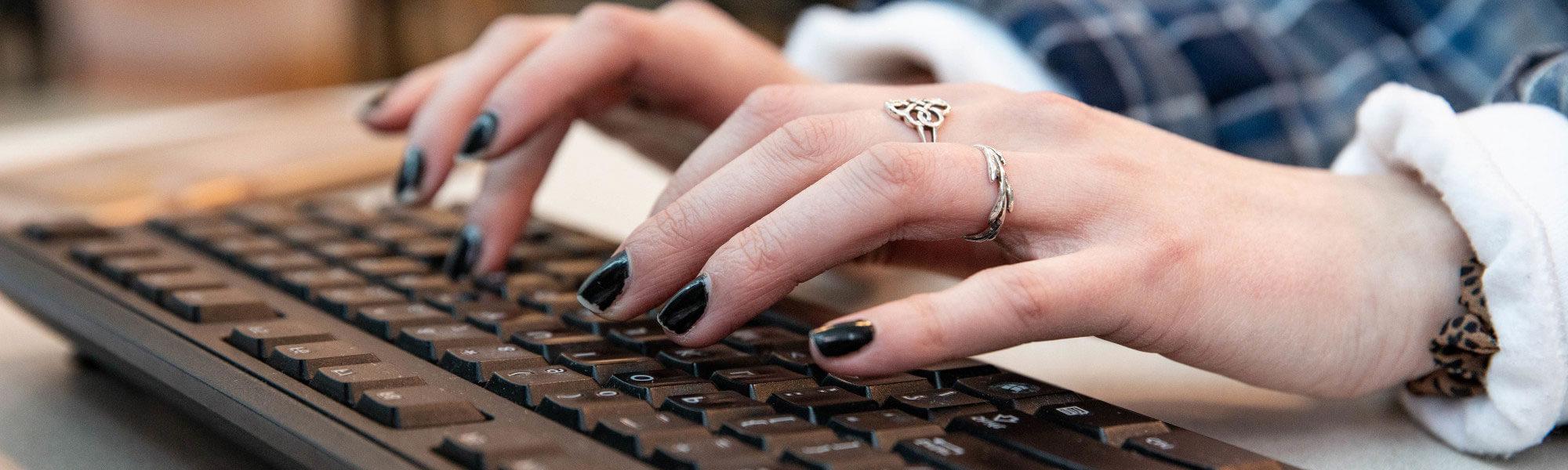 Photo of hands typing on a keyboard.